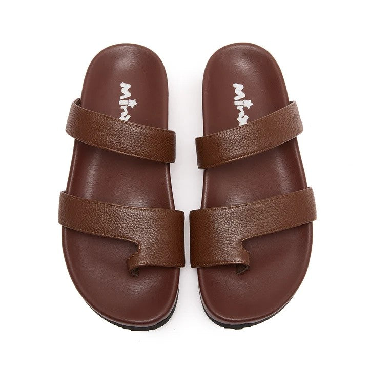 A pair of brown double-strap slide sandals with a pebbled leather-like texture, shown from a top-down view on a white background. The brand name 'Mila' is printed in white on the insole of each sandal.