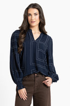 Woman wearing a navy blue blouse with white patterns on a white background