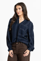 Woman wearing a dark blue blouse with white lines on a white background