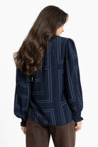 Woman wearing a dark blue blouse with white geometric patterns on a white background