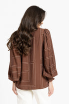Rear of women in brown blouse