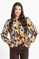Woman wearing a patterned blouse with long sleeves on a white background