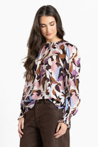 Woman wearing a patterned blouse with long sleeves on a white background