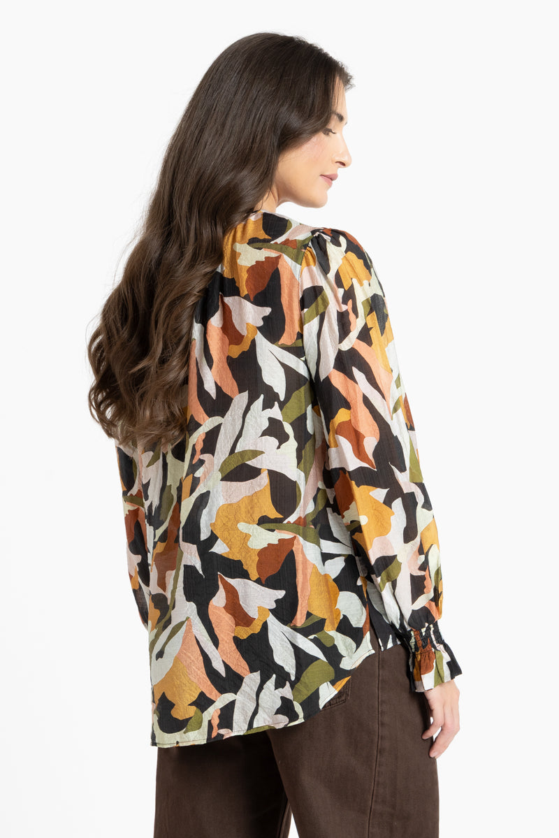 Woman wearing a patterned blouse with long sleeves on a white background