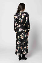 Woman wearing a black floral dress against a white background