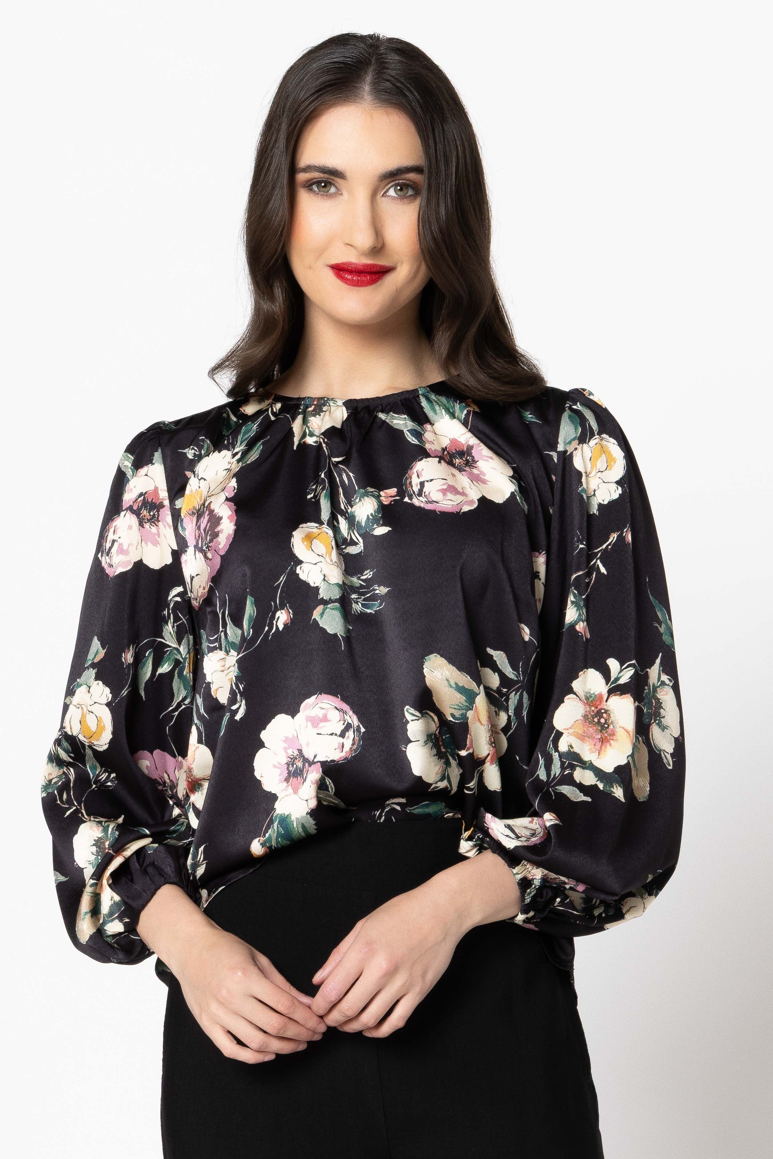 Woman wearing a black floral blouse against a white background