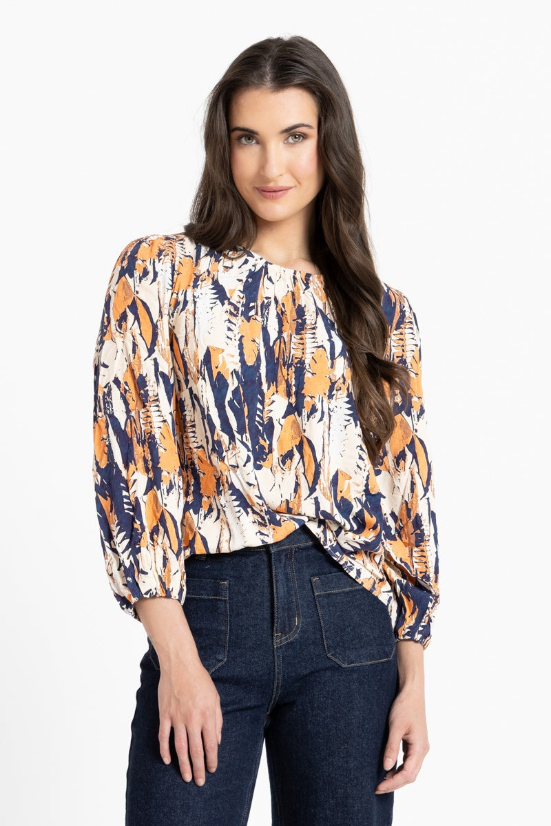 Woman wearing a patterned blouse and jeans on a white background