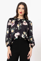Woman wearing a black floral blouse against a white background