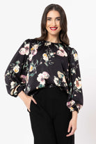 Woman wearing a black floral blouse against a white background