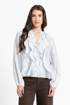 Woman wearing a white blouse with ruffled details on a white background