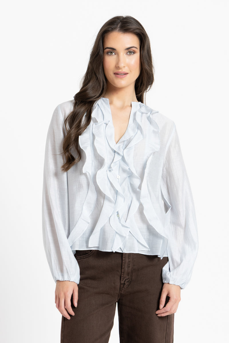 Woman wearing a white blouse with ruffled details on a white background
