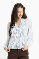 Woman wearing a light blue patterned blouse on a white background