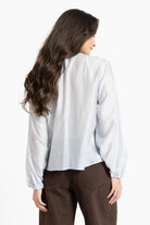 Woman wearing a white blouse and brown pants on a white background