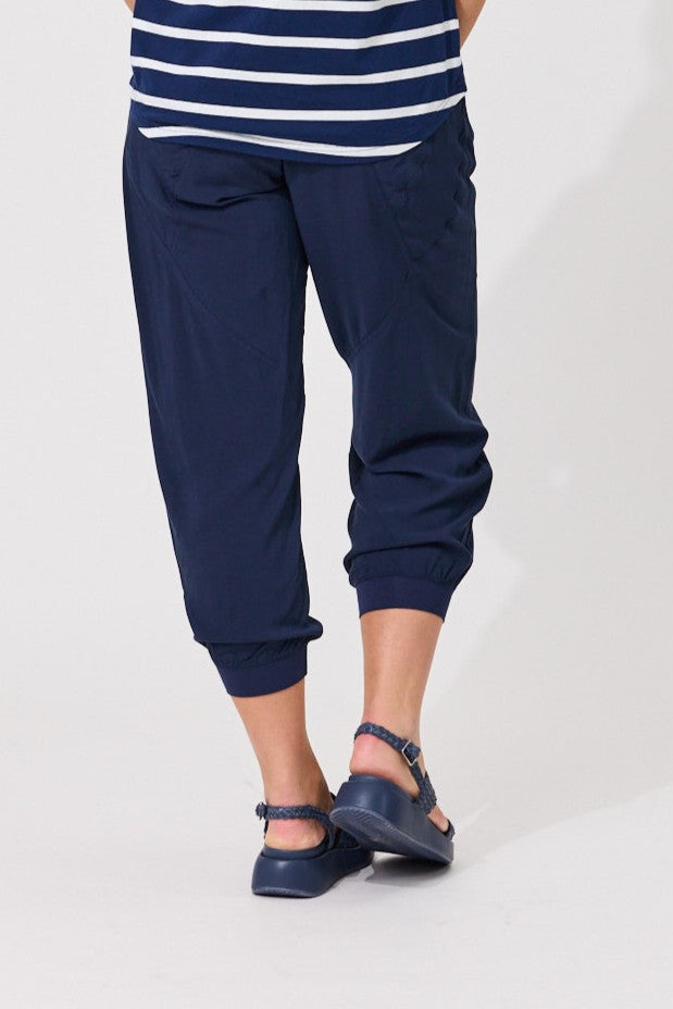 A person wearing navy blue jogger-style pants with a striped navy and white top and navy shoes, shown from the waist down against a plain light background.