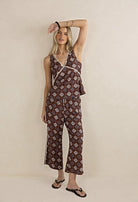 Woman wearing a patterned jumpsuit against a beige background
