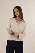 Woman wearing a beige cardigan against a plain background