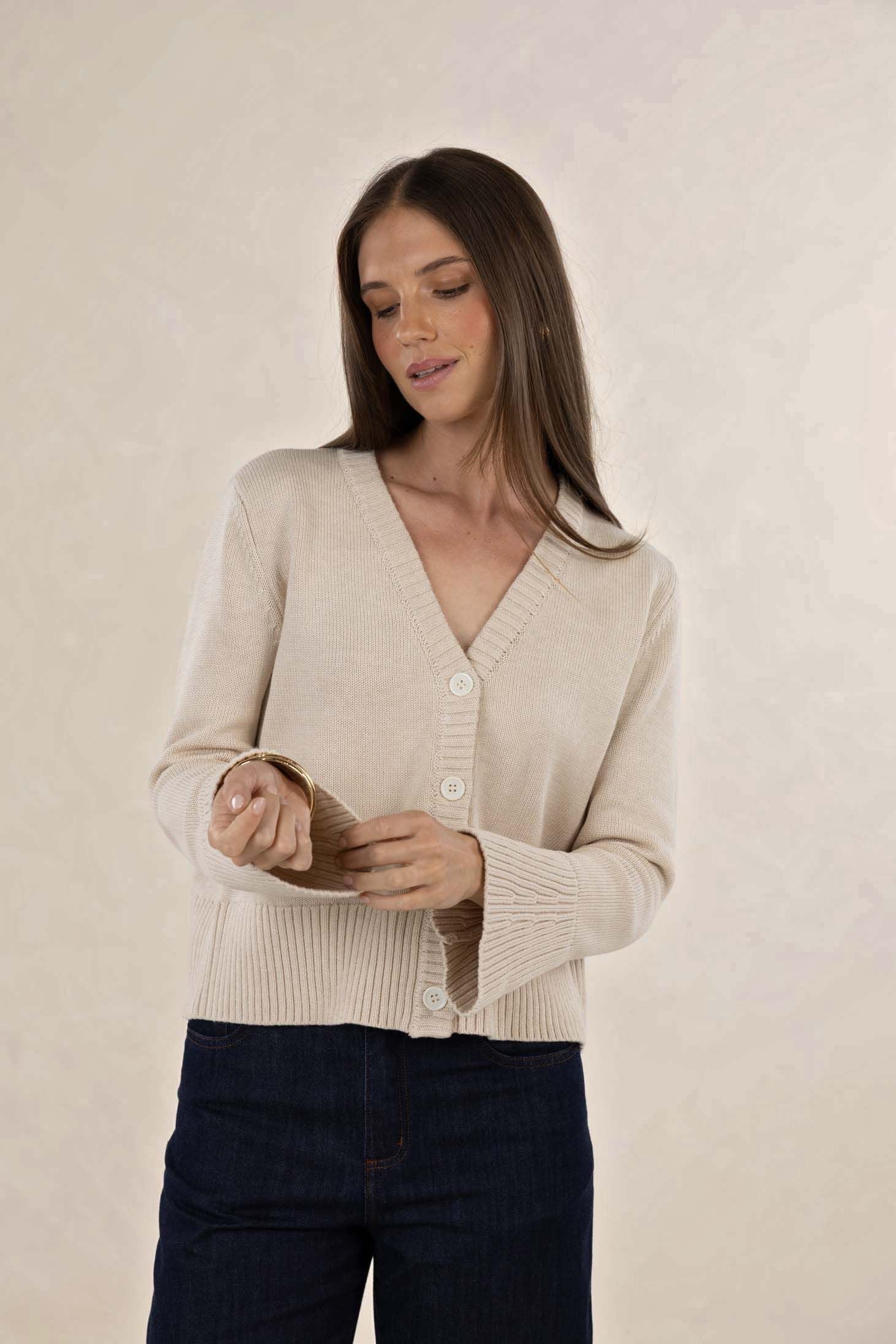 Woman wearing a beige cardigan against a plain background