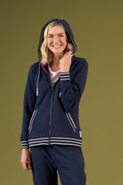Woman wearing a navy blue tracksuit with white accents on a green background