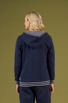Person wearing a navy blue hoodie with white trim on a green background