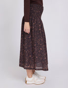 Person wearing a dark floral skirt on a white background