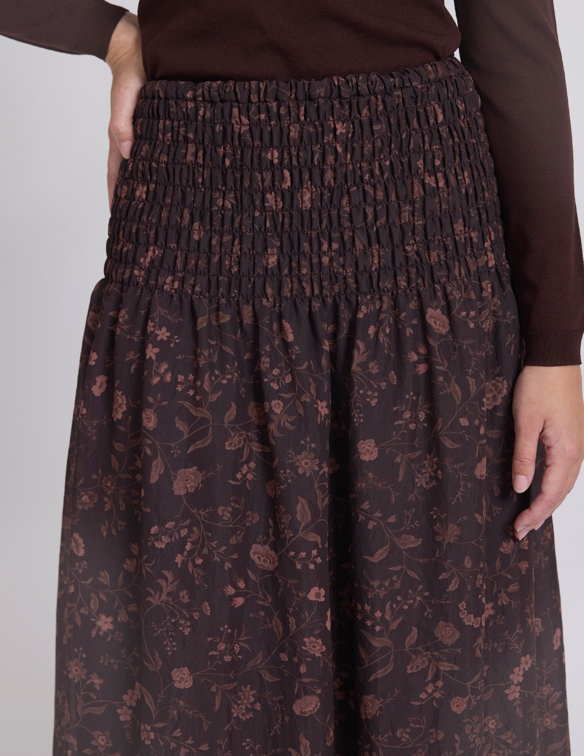 Brown floral-patterned skirt worn by a person on a white background