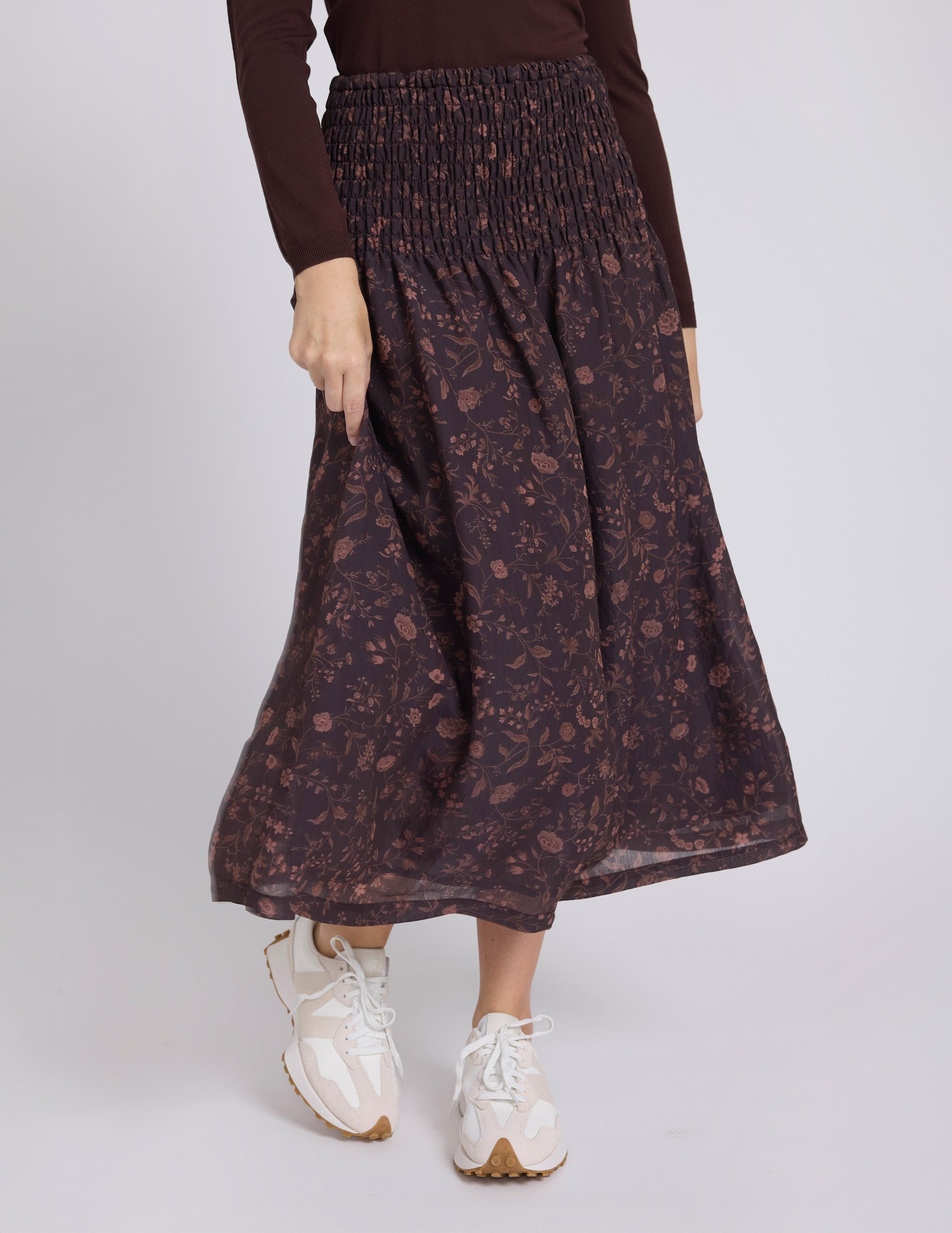 Person wearing a patterned skirt with a plain background
