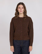 Woman wearing a brown button-up sweater against a white background