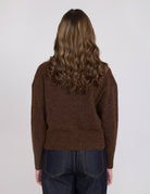 Person wearing a brown sweater from behind on a white background