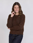 Woman wearing a brown sweater against a white background