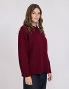 Woman wearing a burgundy sweater against a white background