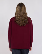 Person wearing a burgundy sweater on a white background