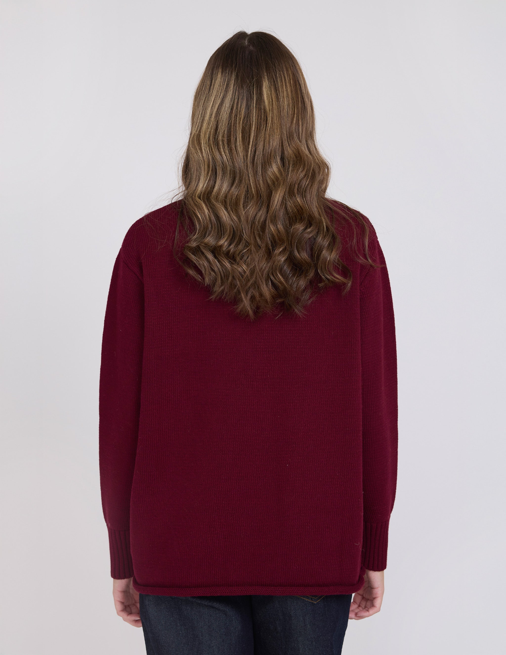Person wearing a burgundy sweater on a white background