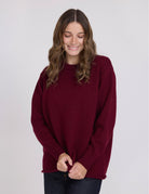Woman wearing a burgundy sweater against a plain background