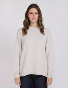 Woman wearing a beige sweater against a plain background