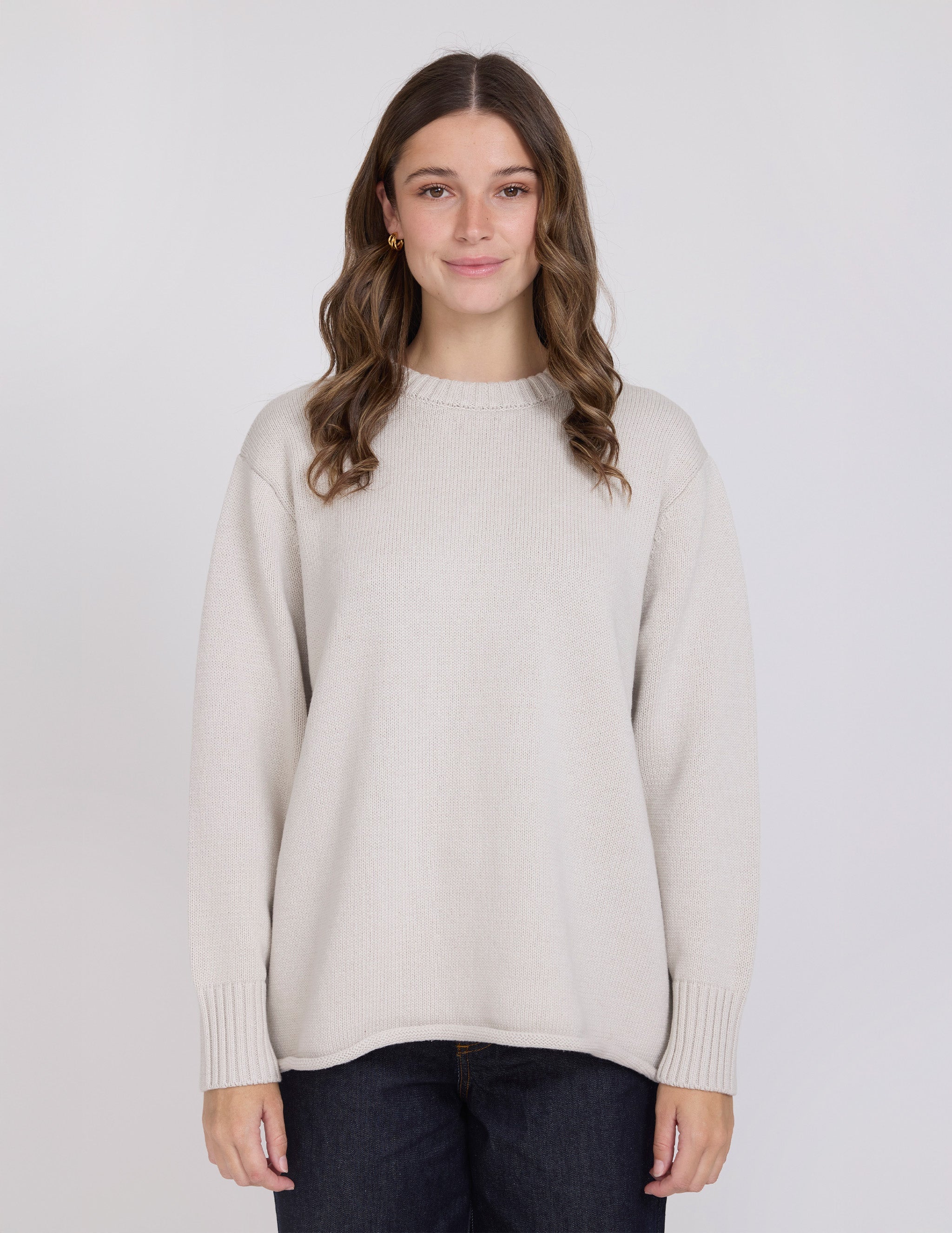 Woman wearing a beige sweater against a plain background