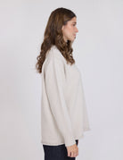 Woman wearing a beige sweater against a white background