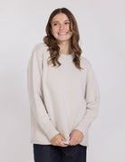 Woman wearing a light beige sweater against a white background