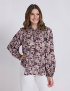 Woman wearing a floral blouse with long sleeves on a white background