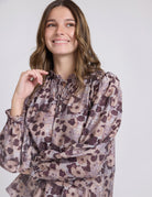 Woman wearing a floral blouse against a plain background