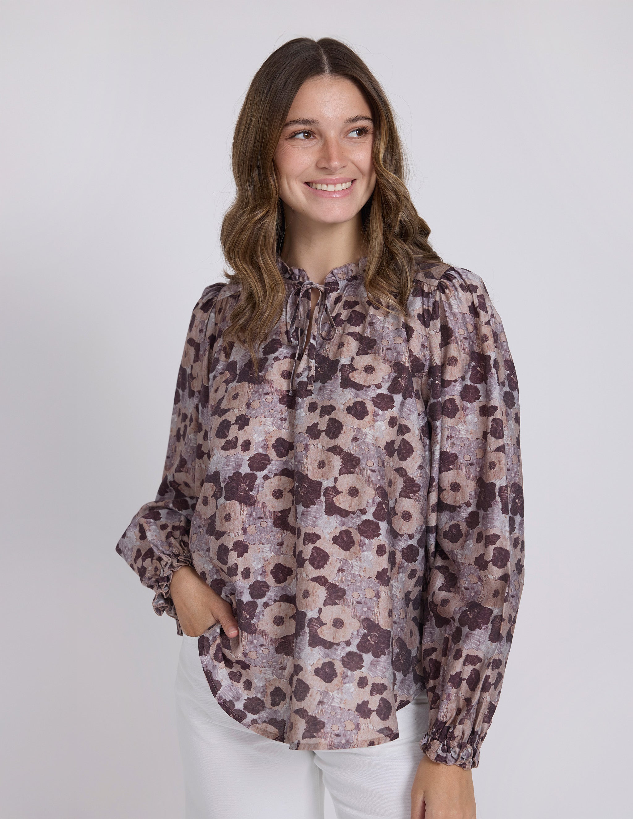 Woman wearing a floral blouse against a plain background