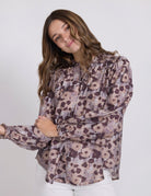 Woman wearing a floral patterned blouse against a white background