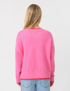 Person wearing a pink sweater with a plain background