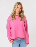 Woman wearing a pink sweater and blue jeans on a white background