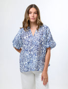 Women wearing a blue floral top in front of a white background.