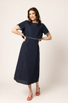Women wearing a navy coloured maxi dress in front of a neutral background