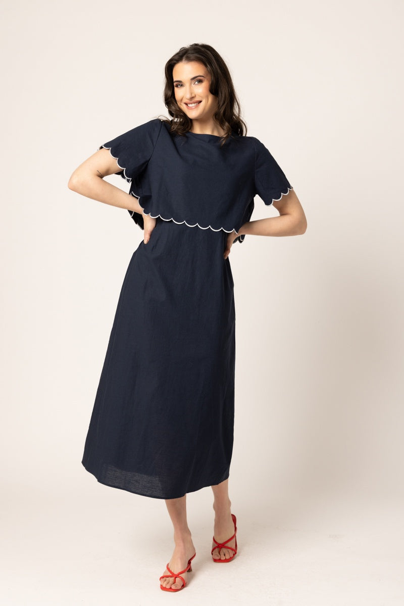 Women wearing a navy coloured maxi dress in front of a neutral background