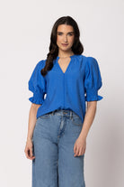 Women wearing a blue blouse in front of a nuetral background