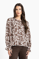 Woman wearing a brown and beige floral blouse against a white background