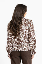 Woman wearing a brown and white floral blouse on a white background