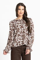 Woman wearing a brown and white floral blouse on a white background